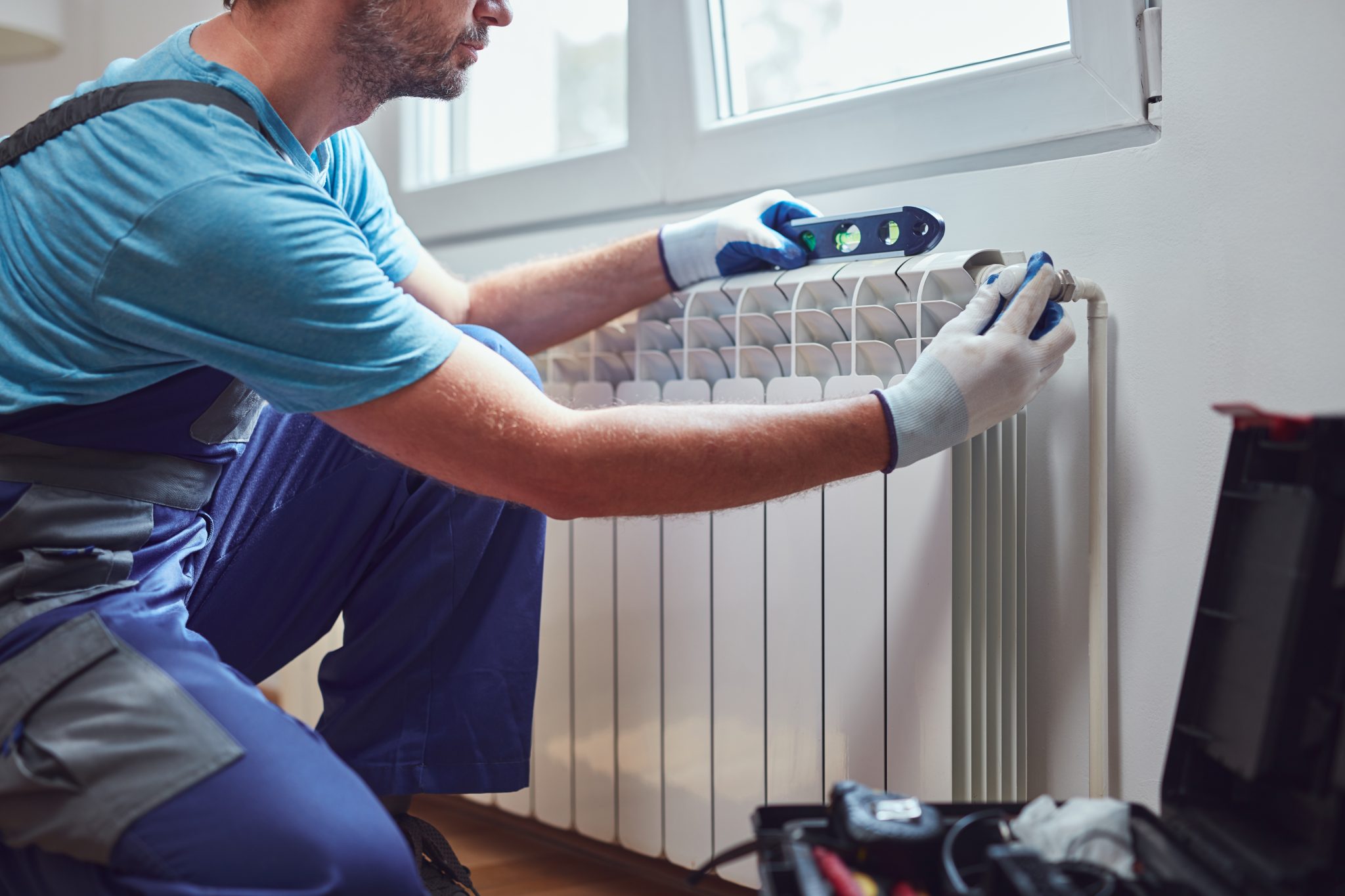 central heating mechanic and handyman fixing home radiator, gas