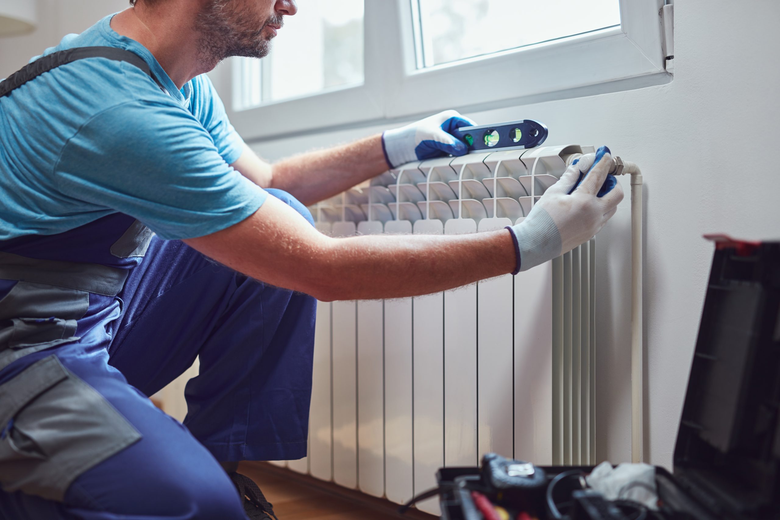 central heating mechanic and handyman fixing home radiator, gas